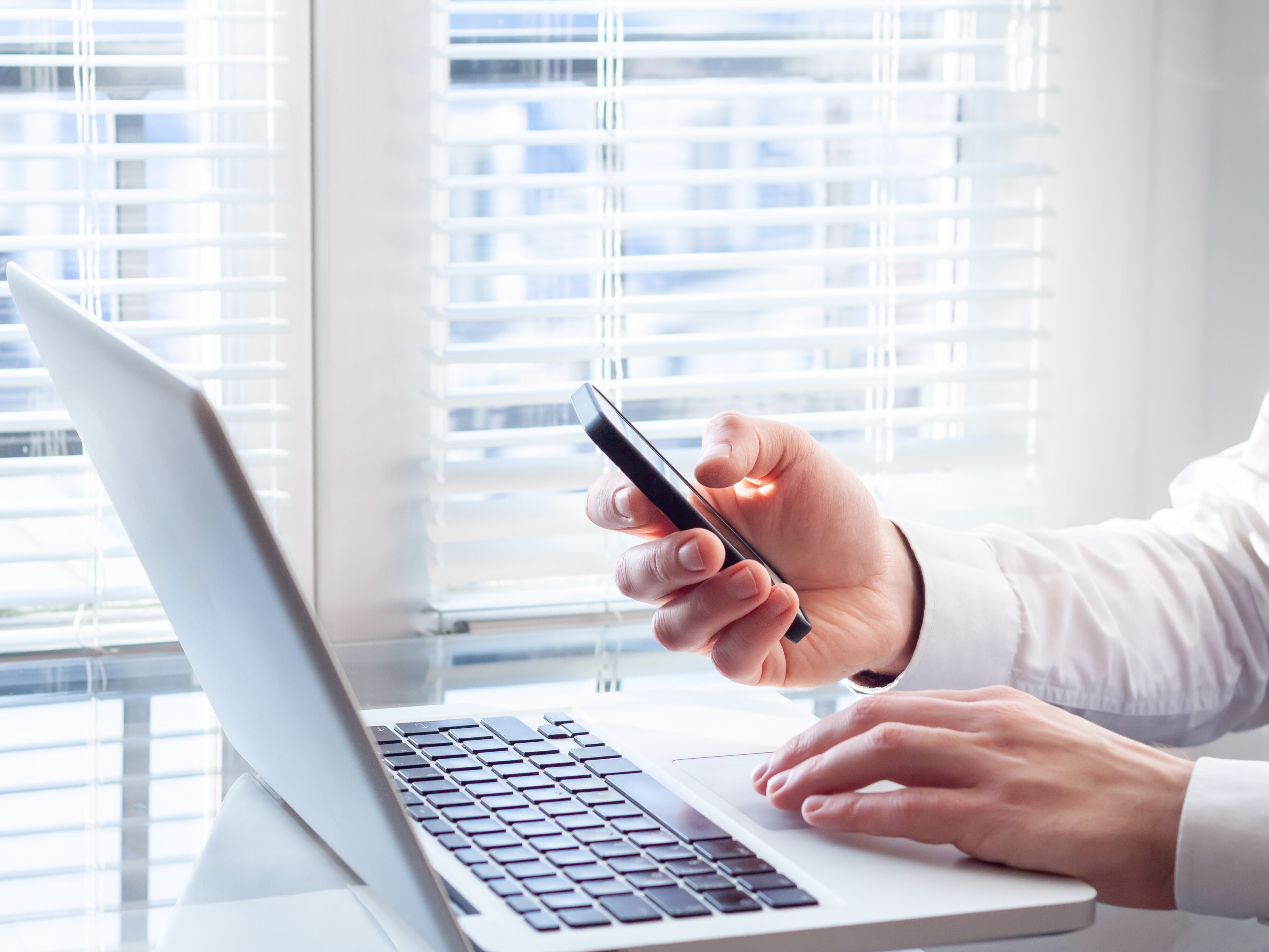 Businessman working with laptop and smartphone, bright office, f